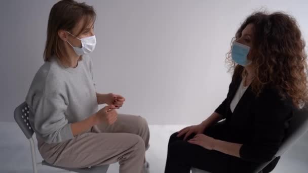 Зустріч жінок у масках в офісі психотерапевтів під час пандемії. Дівчата сидять парами один навпроти одного і розмовляють в офісі психологів. Психологічна допомога під час ковадла-19 — стокове відео