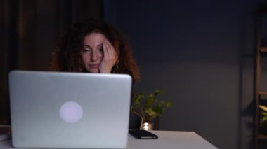 Mature attractive woman in a black business suit is working in the office late at night. Working difficulties and overworking concept