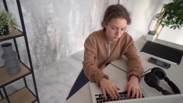 Serious teen girl working with laptop in coworking space. Doing homework, chatting with friends on social networks, surfing the Internet — Stock video