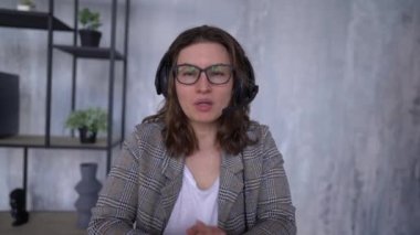 Front view of business woman wearing headset working in office to support remote customer or colleague. Call center, telemarketing, customer support agent provide service on video conference call