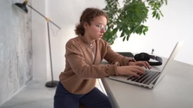 Side view of serious teen girl working with laptop in coworking space. Doing homework, chatting with friends on social networks, surfing the Internet