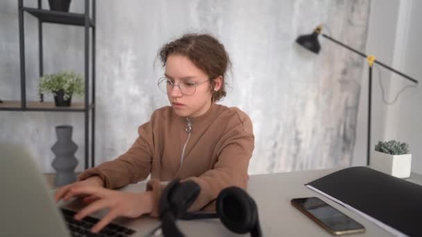 Afstandsonderwijs. Schoolmeisje studeren online met behulp van laptop. Studenten dragen een koptelefoon terwijl ze internet kijken. Toekomstige programmeur om te leren programmeren. Kind speelt op de computer — Stockvideo