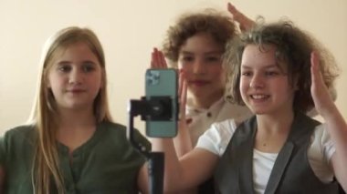 Kameranın önünde dans eden neşeli sınıf arkadaşlarının portresi. Kızlar ve erkek video blogcuları tatilde sınıfta trendleri yakalıyorlar