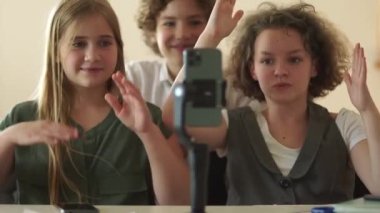 Schoolchildren and smartphone in class in school. Children and teenagers watch videos and repeat dances in front of a smartphone camera
