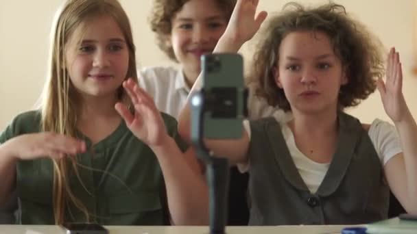 Schoolchildren and smartphone in class in school. Children and teenagers watch videos and repeat dances in front of a smartphone camera — Stockvideo