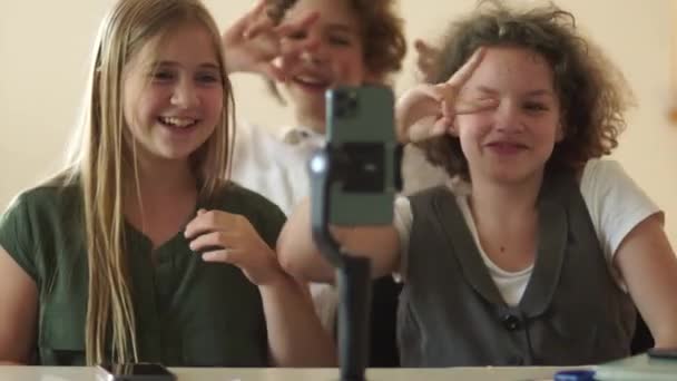 Les adolescents rient et dansent devant la caméra d'un smartphone situé sur un trépied. Les écoliers filment les tendances vidéo pour les médias sociaux — Video