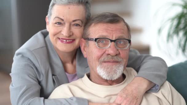 Bliski portret starszego męża i żony. Mężczyzna nosi okulary i szarą brodę, kobieta ma stylową fryzurę na skróty. Szczęśliwy starość pojęcie, dojrzały wiek — Wideo stockowe