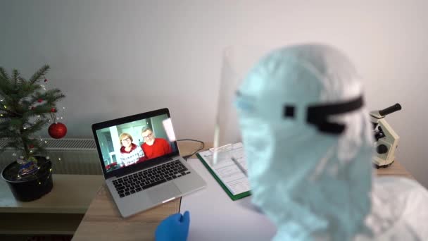 El médico masculino en el laboratorio utiliza un gadget portátil para una videollamada con sus padres. Concepto de navidad en el hospital, investigación de vacunas para covid-19, una nueva cepa de virus. Navidad y covid — Vídeo de stock