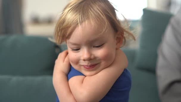 Portrait of a happy blondie little boy laughing and hugging himself. Close-up face of charming little blond boy with blue eyes. Portrait of cute Caucasian child. Happy smiling kid enjoying childhood — Stock Video