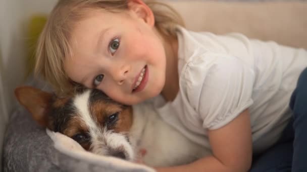 Щасливий хлопчик обіймає собаку Джек Рассел Терер'є рано вранці. Посміхнена дитина, його домашня тварина, що гріється в ліжку щасливе дитинство. — стокове відео