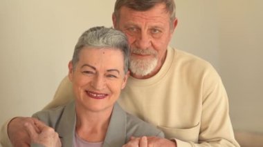 Kameraya bakan yaşlı karı ve kocanın yakın portresi. Şık kısa saçlı bir kadın ve sakallı ve gözlüklü bir adam. Mutlu yaşlı çift