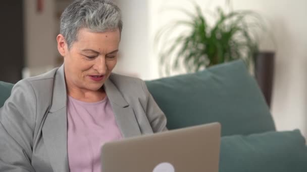 Sorridente bella anziana dai capelli grigi donna shopping online seduta a casa. Felice acquirente femminile fare l'acquisto nel negozio online. Pagamenti facili, servizio di app di banking online — Video Stock