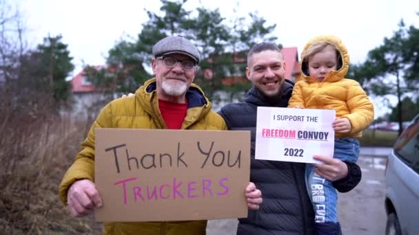 Porträt einer Truckerfamilie. Ein älterer Mann, sein Sohn und sein Enkel unterstützen die Proteste in Kanada. Die Menschen halten Schilder mit Slogans in den Händen. Politische Kundgebung — Stockvideo
