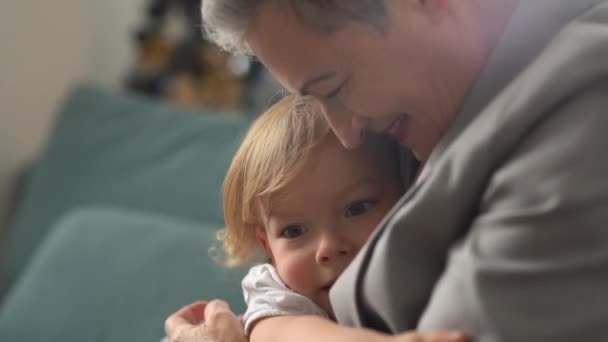 Porträt einer eleganten grauhaarigen Kaukasierin mit Kurzhaarschnitt, die ihren kleinen Enkel umarmt. Glückliche Großmutter und glückliche Kindheit — Stockvideo
