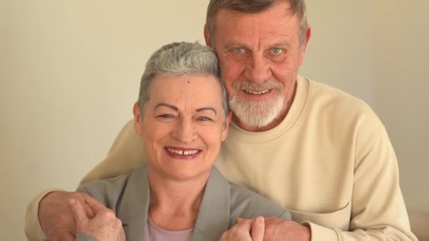 Retrato cercano de los ancianos sonrientes marido y mujer mirando a la cámara. Una mujer con un corte de pelo corto con estilo y un hombre con barba y gafas. Feliz pareja de ancianos celebrando la Navidad — Vídeos de Stock