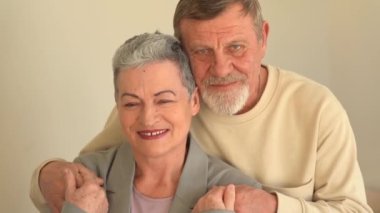 Kameraya bakan yaşlı karı ve kocanın yakın portresi. Şık kısa saçlı bir kadın ve sakallı ve gözlüklü bir adam. Mutlu yaşlı çift Noel 'i kutluyor.