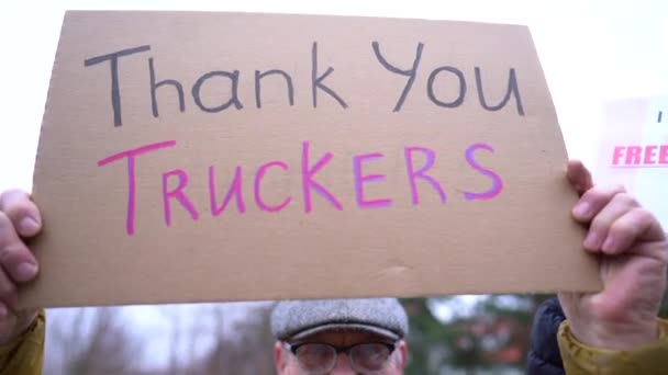 Ein Plakat mit der Aufschrift "Danke Trucker" in den Händen eines älteren Mannes in Winterkleidung und Mütze. Streik zur Unterstützung der Bewegung Freedom convoy 2022 in Kanada — Stockvideo