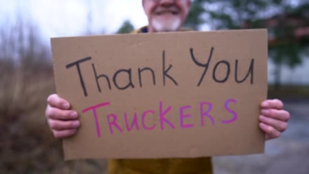 캐나다의 프리덤 호송대 2022를 지원하는 파업. 겨울 옷을 입고 모자를 쓴 노인의 손에 트럭 운전자들이 새겨져 있는 포스터, 감사합니다 — 비디오