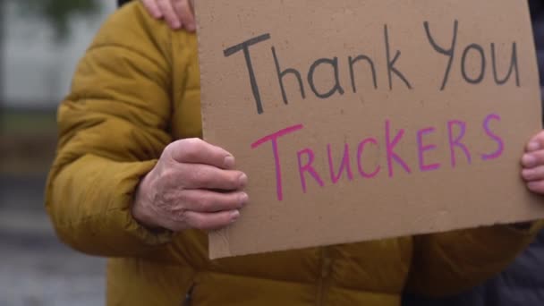 Dos hombres adultos de pie abrazando con un cartel Gracias camioneros. Acción en apoyo del movimiento contra la vacunación Convoy Libertad 2022 en Canadá. Huelga poética, acción pacífica — Vídeo de stock