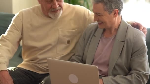 Старшая пара дома использует ноутбук. Семья на пенсии работает над изучением компьютера в социальных сетях. Компьютерная грамотность среди пожилых людей — стоковое видео