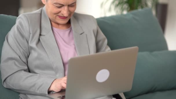 Mooie gelukkige zakenvrouw met kort kapsel die op afstand van huis werkt. gelukkig oud senior vrouw oma met behulp van laptop computer thuis — Stockvideo