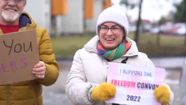一个穿着保暖衣服的男人和一个女人拿着标语牌，上面写着：谢谢卡车司机和自由车队。支持加拿大反疫苗运动的人的户外画像 — 图库视频影像