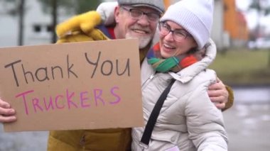 Kanada 'da Ottawa' daki aşı karşıtı protestolara destek olmak için toplanın. Kalın giysili bir kadın ve bir erkek yazıtlarla tabela tutarlar. Teşekkürler kamyoncular ve özgürlük konvoyu.