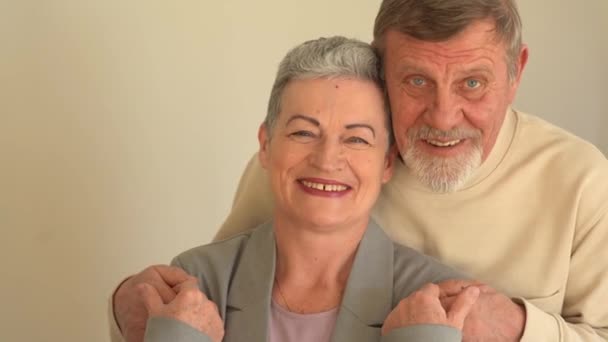 Близький портрет усміхненого літнього чоловіка і дружини, що дивиться на камеру. Жінка зі стильною короткою стрижкою і чоловік з бородою і окулярами. Щаслива літня пара святкує Різдво — стокове відео
