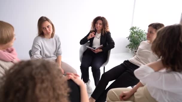 Ženy různého věku spolu mluví, tleskají si a sdílejí své zkušenosti a podporu během terapeutického setkání v kanceláři psychologa nebo trenéra — Stock video