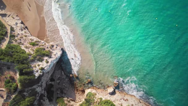 地中海沿岸への美しい航空ビュー ターコイズブルーの波がゆっくりと砂のビーチに流れ込み 絵のように美しい切り立った崖がある — ストック動画