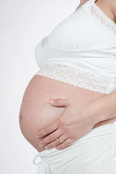 Vientre de la mujer embarazada con las manos en el pecho sobre fondo blanco —  Fotos de Stock