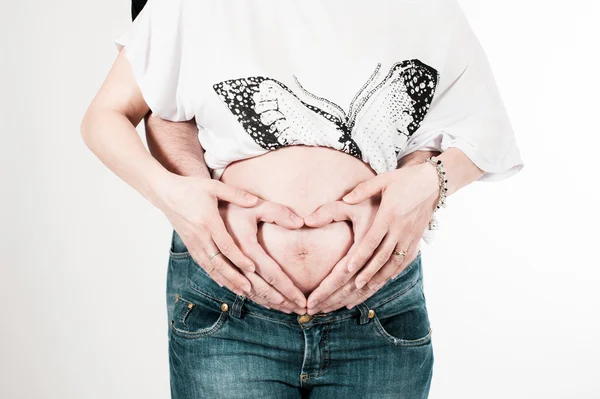 Feliz embarazada y padre manos en forma de corazón en el vientre — Foto de Stock