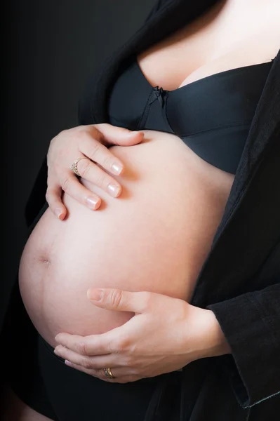 Buik van zwangere vrouw met handen op de borst op witte backgr — Stockfoto