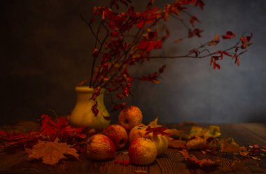 Solmuş elmalar, kuru yapraklar ve masada bir gül kalçası dalı.