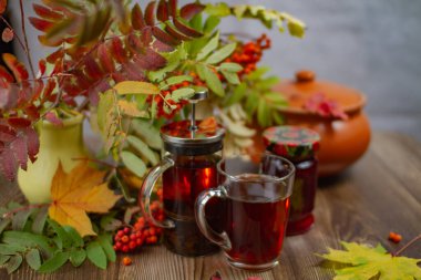 Sıcak çay, çaydanlık ve reçel kavanozu masada.