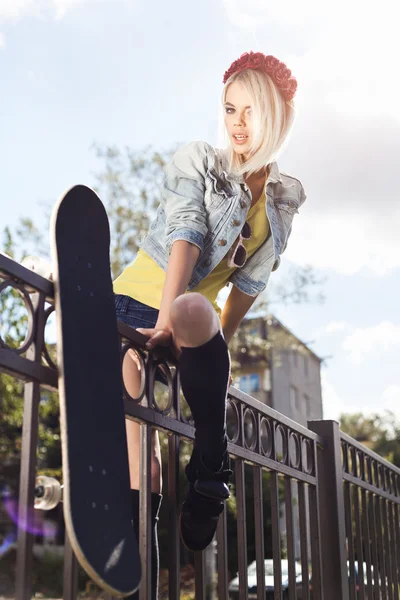 Young woman climbs over fence — Stock Photo, Image