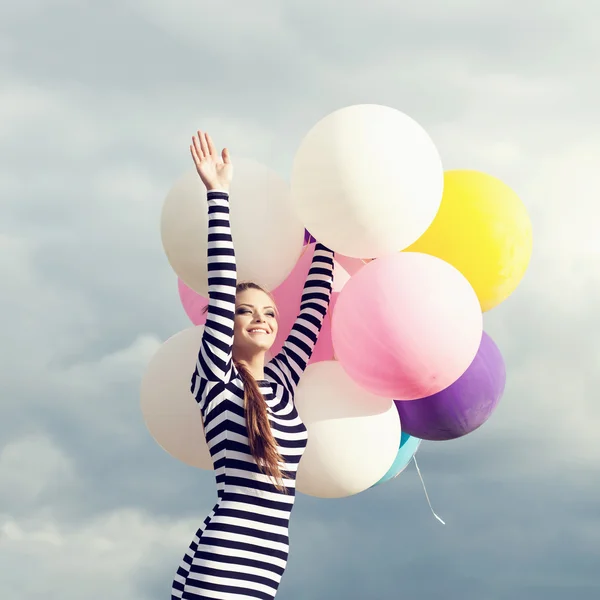 Счастливая молодая женщина с цветными латексными шариками — стоковое фото