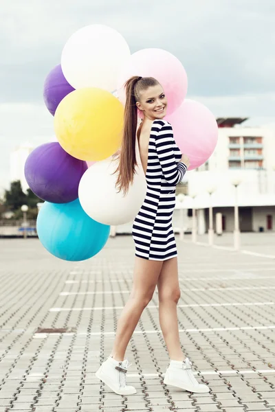 Happy young woman with colorful latex balloons — Stock Photo, Image