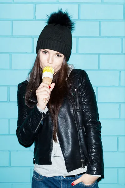 Young woman eating ice cream over blue brick wal — Stock Photo, Image