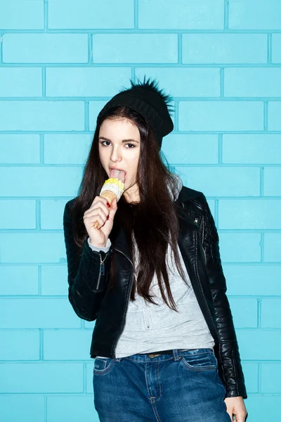 Mujer joven comiendo helado sobre wal ladrillo azul — Foto de Stock