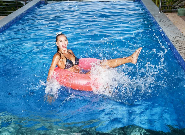 Mujer flotando en el tubo interior en la piscina y divertirse — Foto de Stock