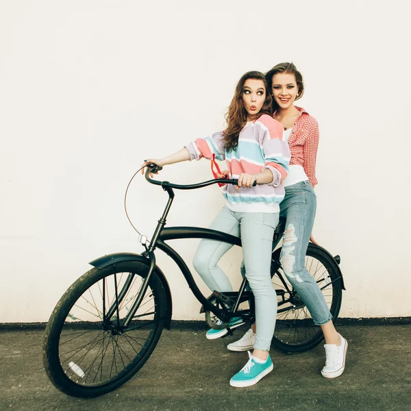 Two hipster girl friends with bicycle. — Stock Photo, Image