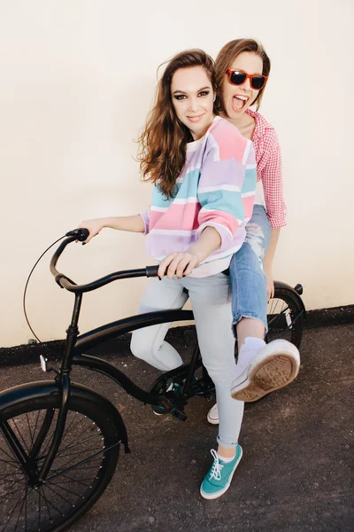 Two hipster girl friends with bicycle. — Stock Photo, Image
