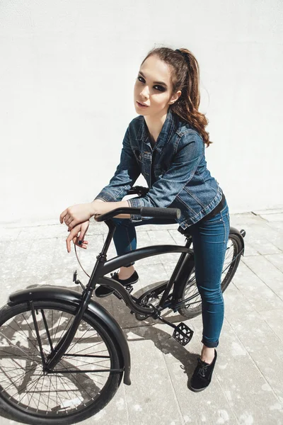 Молодая женщина хипстер стоит с черным велосипедом — стоковое фото
