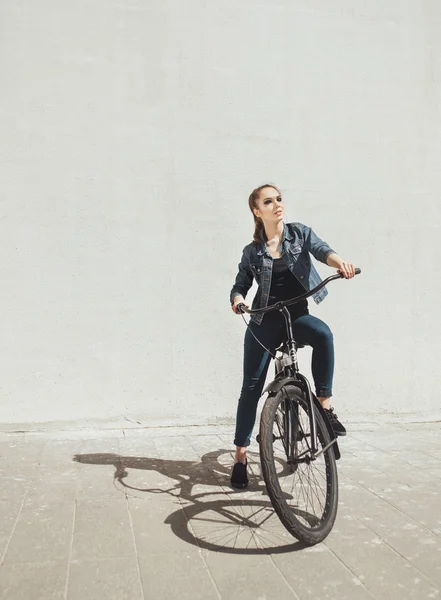 Молодая женщина хипстер стоит с черным велосипедом — стоковое фото