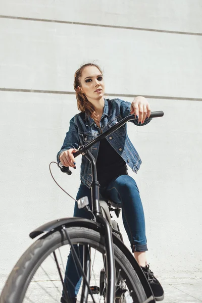 Young woman hipster standing with black bike — Stock Photo, Image