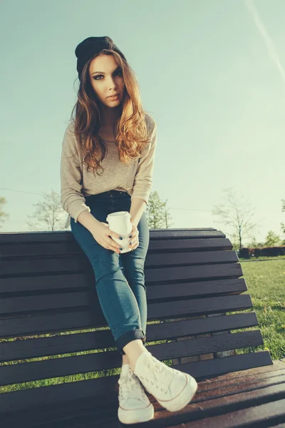 Menina bonita sentada em um banco — Fotografia de Stock