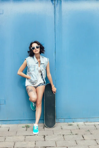 Giovane donna bruna in posa con skateboard — Foto Stock
