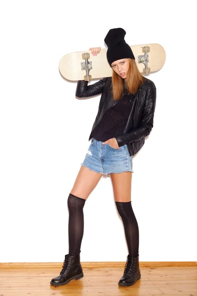 Trendgirl in schwarzer Jacke und Mütze mit Skateboard — Stockfoto