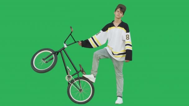 极端的骑自行车的人穿着冰球球衣站在绿屏背景的Bmx自行车 身材魁梧的年轻人骑自行车在彩色钥匙上玩得很开心 4K原始录像镜头 — 图库视频影像
